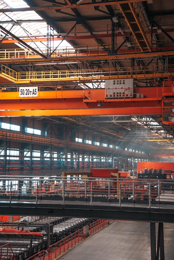 Spacious factory interior featuring large overhead cranes and metal walkways.