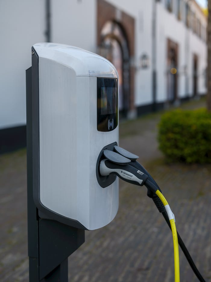 Close-up of an electric vehicle charging station with cable and plug outdoors.