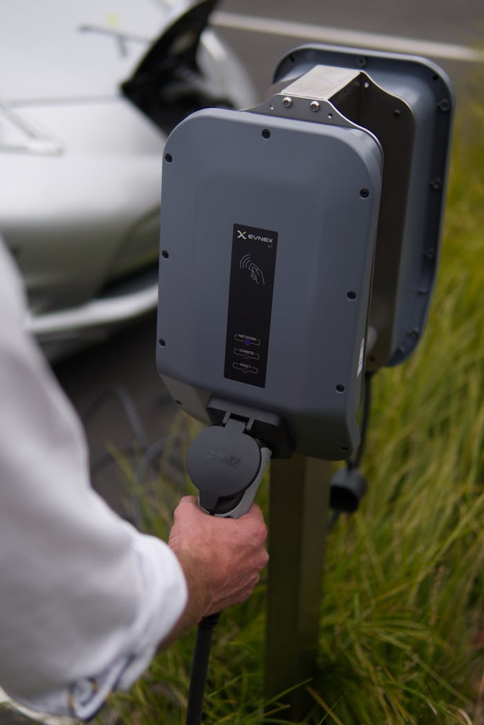 Close-up of a hand connecting an electric vehicle at a charging station in Christchurch, New Zealand.